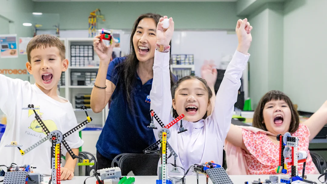 Children and instructor celebrating completed robotics projects